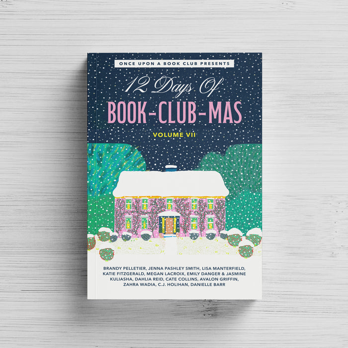 A paperback copy of the 12 Days of Book-Club-Mas Volume VII sits on a white wood background.