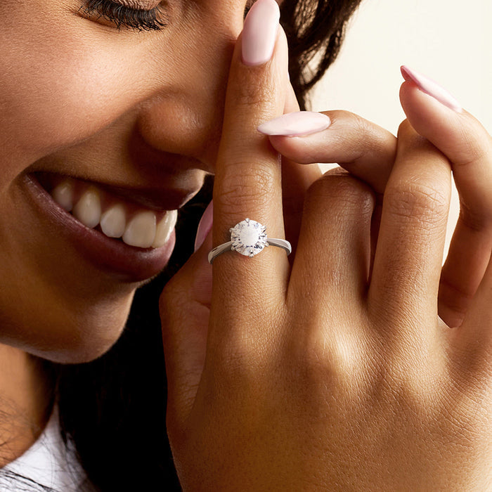 Sterling silver moissanite solitaire ring on hand with round center stone and prongs