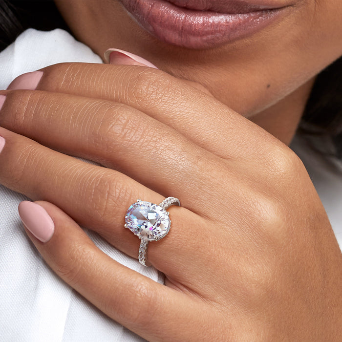 Sterling silver oval CZ ring on hand with prong-set center stone and pave shanks