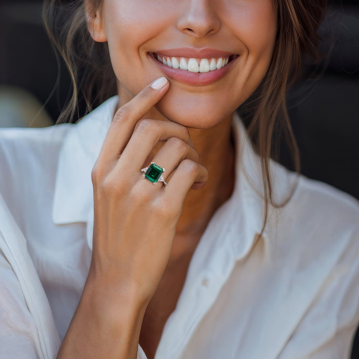 Sterling silver ring with green emerald-cut center and small CZ accents on hand