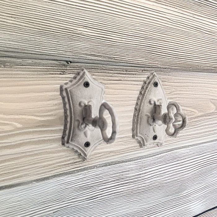 Two gray key hooks against a gray wood wall.