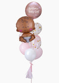 A baby balloon bouquet with a tan baby and mixed pink latex and mylar balloons