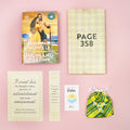 Flatlay of Highland Destiny book, yellow plaid gifts for Pages 358 and 73, and matching accessories.
