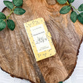 Winnie-the-Pooh book-themed clutch with yellow bee design on a wooden surface with green leaves.