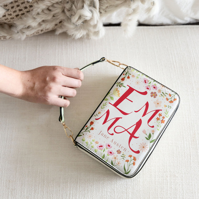"Emma" book-inspired floral purse resting on a beige surface with a knit blanket in the background.