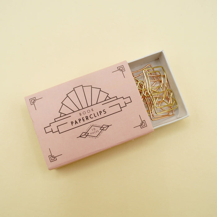 Pink box of gold book-shaped paperclips, partially open to reveal clips, labeled "10 pieces".