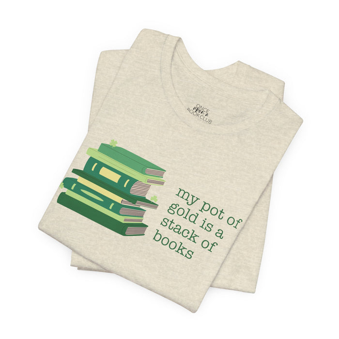 Beige t-shirt with green stack of books and clovers graphic and text "my pot of gold is a stack of books" on a white background