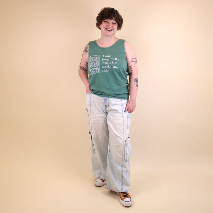 Woman wearing a green tank top with text that reads 'I like long walks down the bookstore aisle' and bookshelf graphic on a beige background.