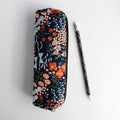 A navy blue pencil pouch with an embroidered floral pattern next to a matching pencil.