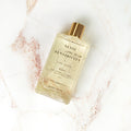Sense and Sensibility bubble bath bottle with a gold cap displayed on a marble surface.