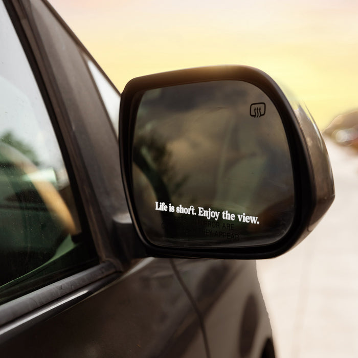 Car side mirror with 'Life is short. Enjoy the view.' quote