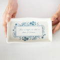 A ceramic trinket dish featuring blue floral pattern and a quote "There is magic in what we choose to treasure."