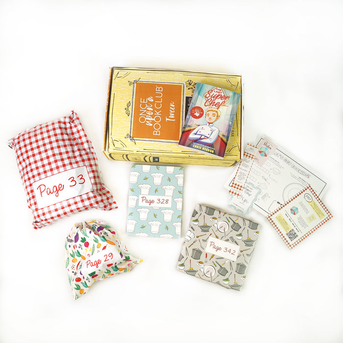 A copy of "The Last Super Chef" by Chris Negron on a yellow OUABC box surrounded by wrapped gifts and paper items.