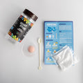A Heart Stone Crystal Growing Kit jar next to the supplies included: instruction page, packet of crystals, spoon, and cup.