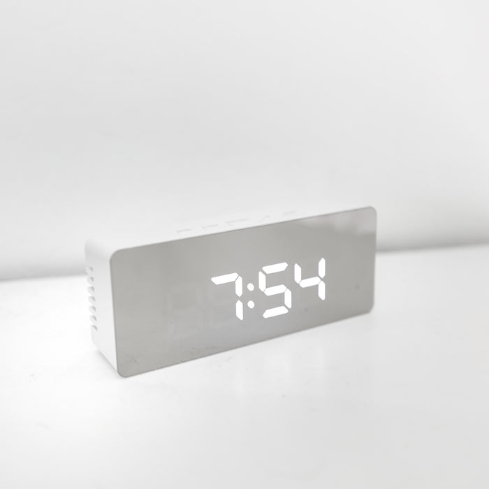 A silver alarm clock with the time at 7:54.