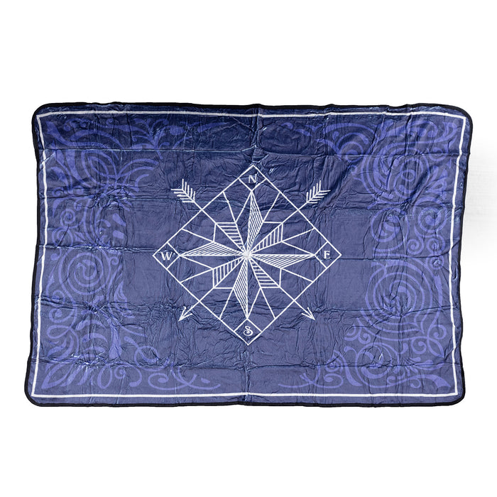 A dark blue fleece blanket with a swirl pattern and a white compass in the middle. The compass has two arrows pointing diagonally down, one southwest and one southeast.
