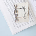 A set of two silver dragonfly-shaped hair pins lay on an open book