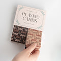 An open box showing two sets of standard size playing cards. The cards have a black and brown dragonfly pattern on their backs.