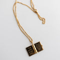 A gold necklace with an open book. The book's pages are also gold and each page has a different quote engraved on it.