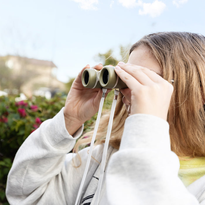 Person using binoculars outdoors with a blurred natural background