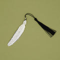 A silver feather bookmark with a black tassel.