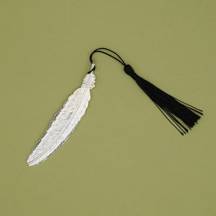 A silver feather bookmark with a black tassel.