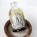A glass container labeled The Wizard's Miracle Elixir Bubble Bath. There is dark green liquid inside.