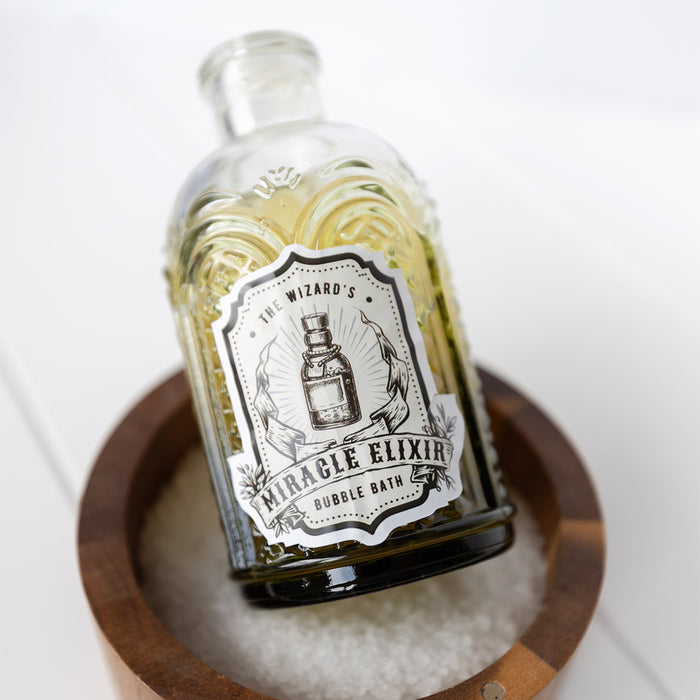 A glass container labeled The Wizard's Miracle Elixir Bubble Bath. There is dark green liquid inside.