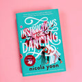 A hardcover copy of Instructions for Dancing by Nicola Yoon sits on a pink background.