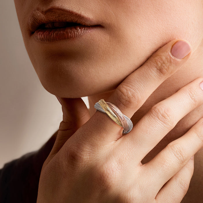 Tri-colored mesh gold ring worn on finger, intertwined orange, yellow, and white bands
