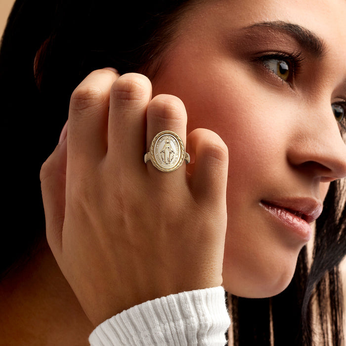 Gold-tone medal ring worn on hand, oval medallion in braided frame