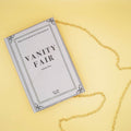Vanity Fair-themed book purse with a gold chain strap, styled against a yellow background.