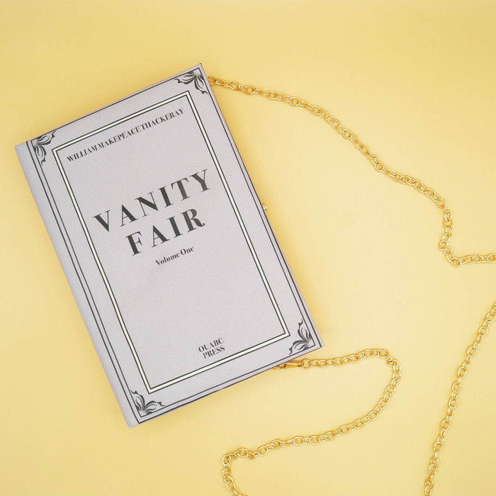 Vanity Fair-themed book purse with a gold chain strap, styled against a yellow background.