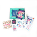 A paperback edition of Nothing Bad Happens Here stands on a green OUABC box. In front of the box are four themed wrapped gifts that match the book cover labeled with page numbers.