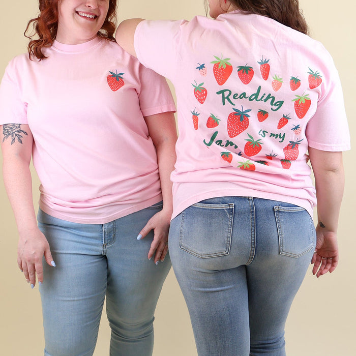Two women wearing pink t-shirts with strawberry designs and text that says 'Reading is my Jam' on a beige background