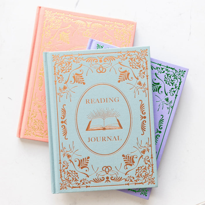 All three reading journal colorways sit in a stack on a white marble counter.