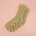 A pair of slipper socks with brown snowflake-shaped grips on the bottom