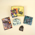 A paperback edition of The Total Eclipse of Nestor Lopez lays on a yellow OUABC box next to a wrapped gift labeled with a page number. In front of the box are four more themed wrapped gifts labeled with page numbers.