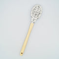 A white silicone cooking spoon with a wooden handle. There is a pattern of kitchen appliances of the silicone part.