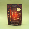 Book cover of The Crimson Throne by Sara Raasch and Beth Revis on a green background.