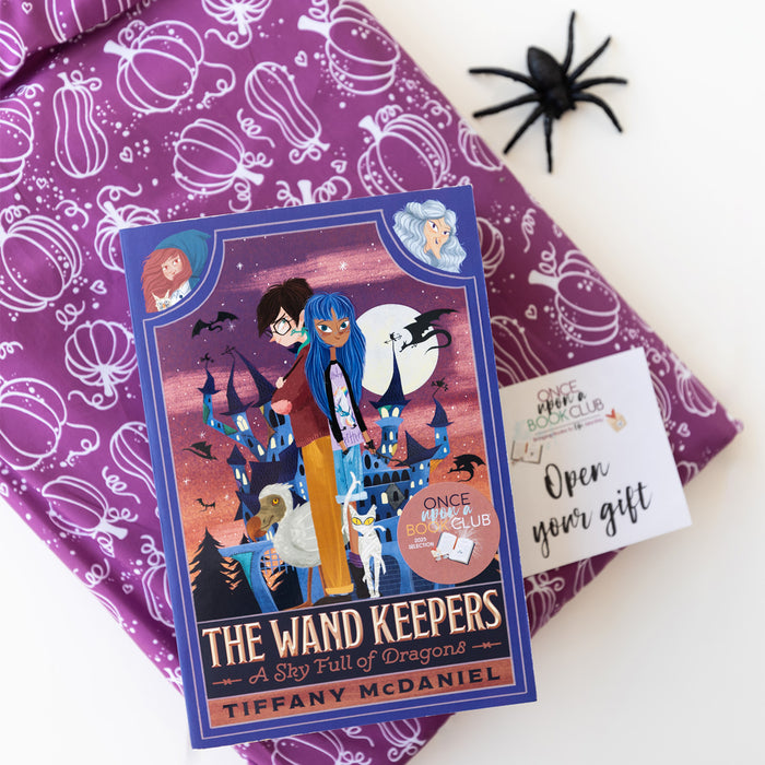 Book titled 'The Wand Keepers' by Tiffany McDaniel on a purple patterned surface with a spider decoration.