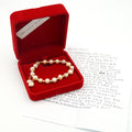 a red felt necklace box is open showing a freshwater pearl & 18k gold bracelet