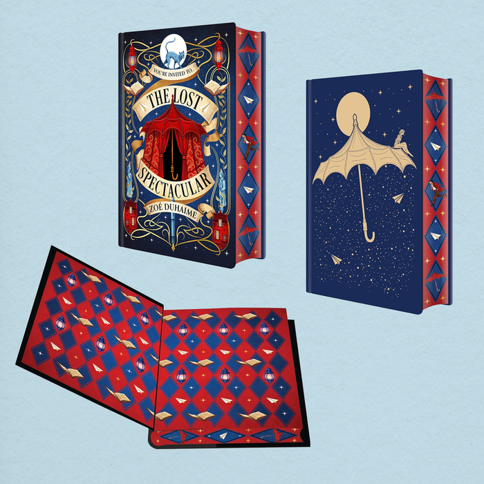 A decorative illustrated book shown from multiple angles on a pale blue background. The cover reads "The Lost Spectacular" and features a dark blue circus-style design with red and gold details, a red-and-blue patterned page edge design, and an open interior spread with matching red-and-blue patterned pages.