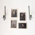 Two black wall scones holding white candles. In between the scones are four portraits of owls in white frames.