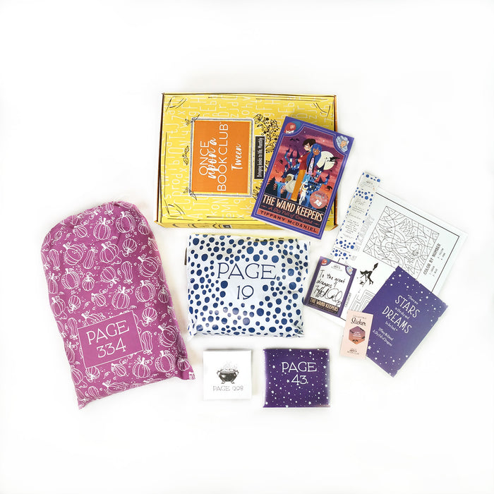 A paperback edition of The Wand Keepers: A Sky Full of Dragon stands on a yellow OUABC box. In front of the box are four themed wrapped gifts labeled with page numbers.