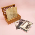 An open wooden box with a note sticking out of it and three black and white old photos next to it